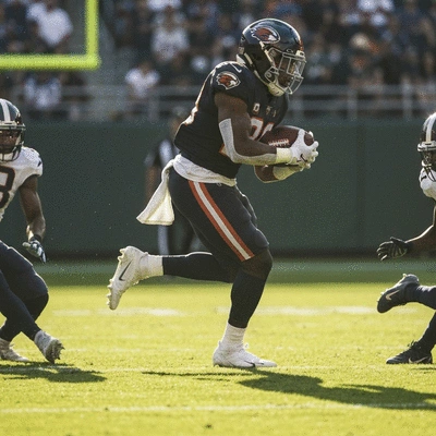 Najee Harris mid-run on a football field, evading defenders.